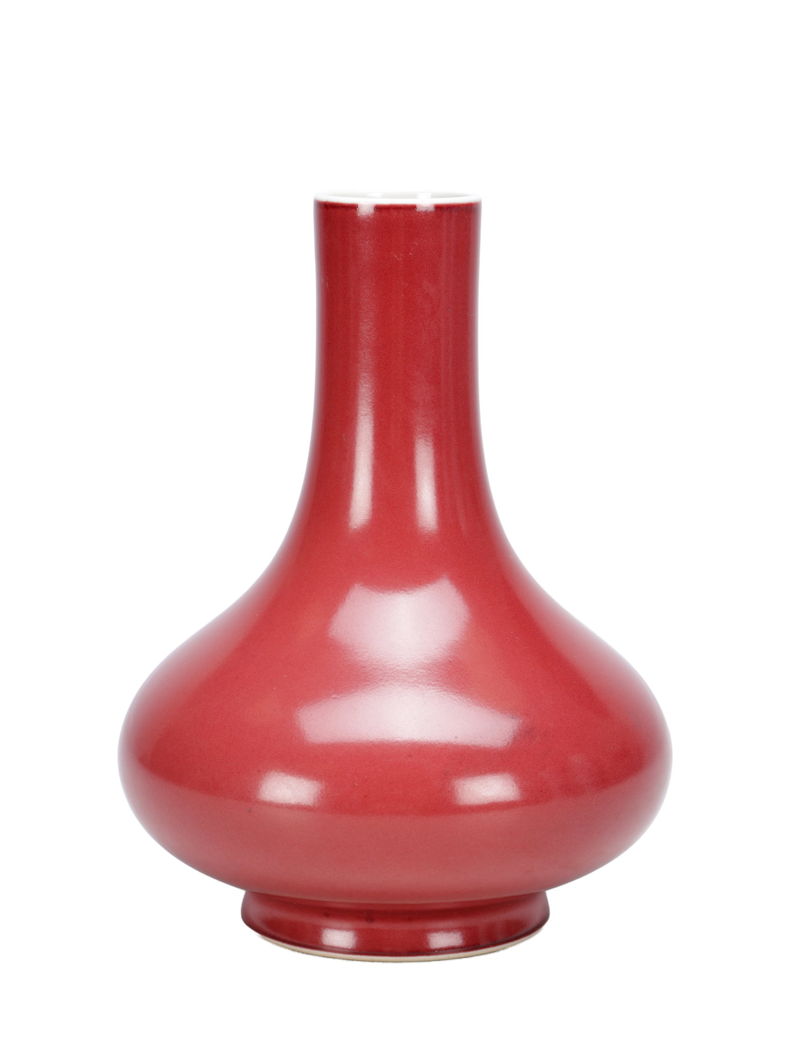 A CHINESE SANG-DE-BOEUF GLAZED PORCELAIN BOTTLE VASE: A CHINESE SANG-DE-BOEUF GLAZED PORCELAIN BOTTLE VASE of pear-shaped body with tall cylindrical neck and short splayed foot, the copper-red glaze evenly applied and thinning to a white rim and foot. (2
