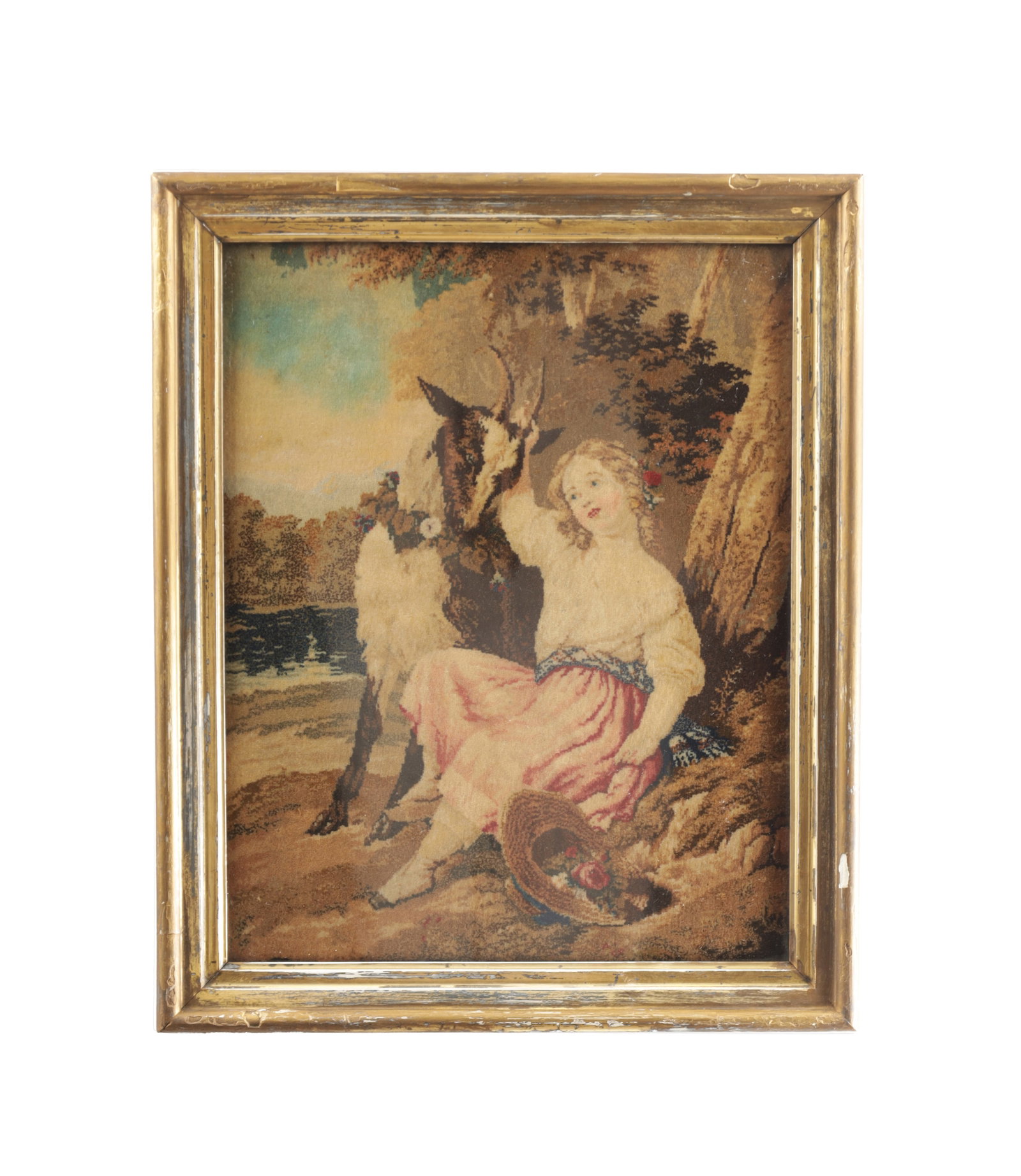 A MID 19TH CENTURY WOOLWORK PICTURE: A MID 19TH CENTURY WOOLWORK PICTURE worked in coloured wools depicting a shepherdess seated beside a goat beneath a tree by a river with a basket of flowers, mounted in a gilt frame. (45cm high, 36cm