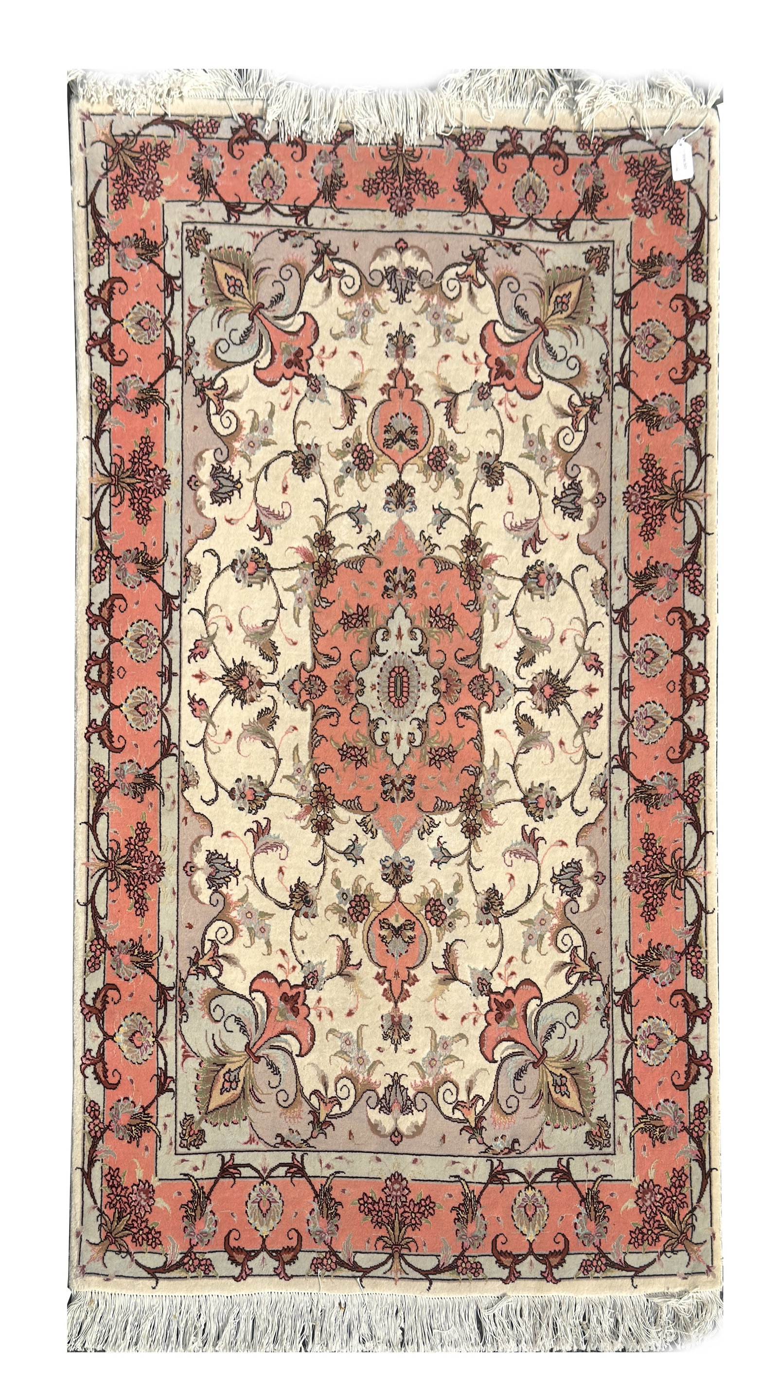 AN IRANIAN HAND KNOTTED CARPET: AN IRANIAN HAND KNOTTED CARPET of rectangular form with a central lobed medallion and scrolling floral field on a cream ground within salmon floral borders, fringed to both ends. (150cm by 103cm )