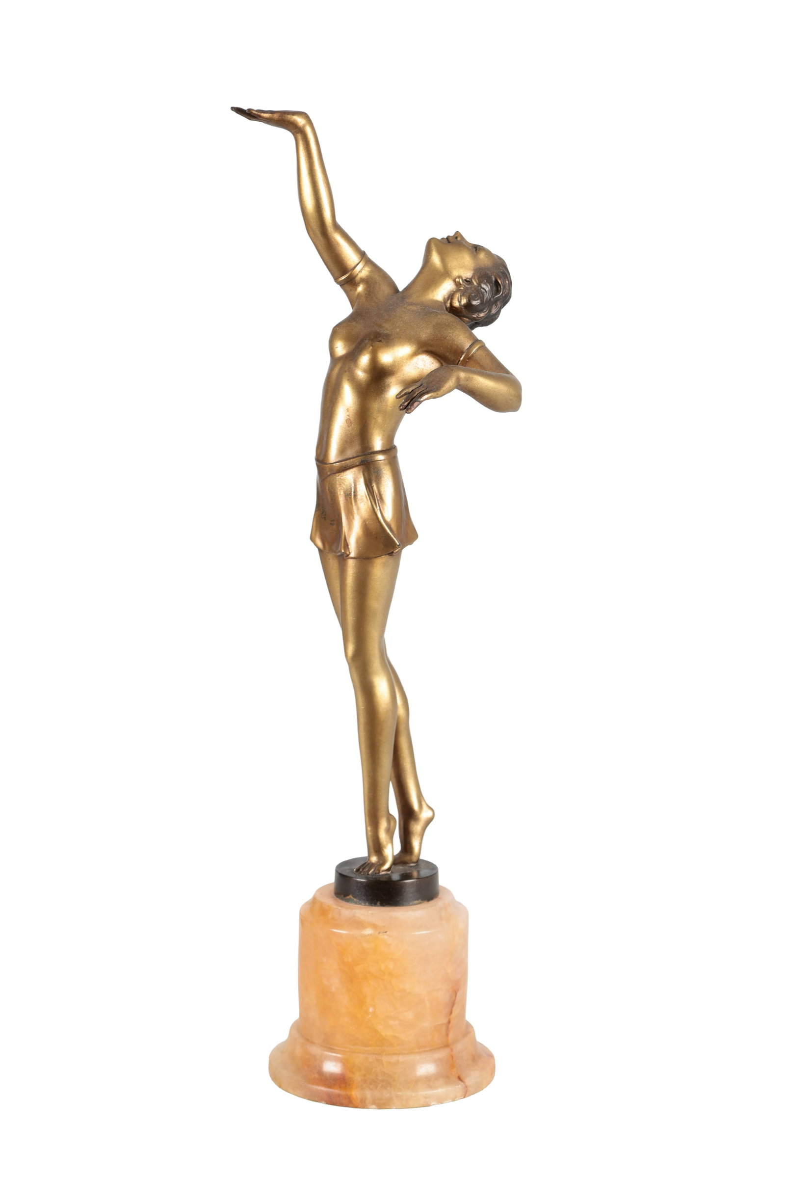AN ART DECO GILT METAL FIGURE OF A DANCER ON AN ONYX BASE: AN ART DECO GILT METAL FIGURE OF A DANCER ON AN ONYX BASE depicting a stylised female with one arm raised and head inclined, the figure on a circular black socle above a cylindrical honey onyx