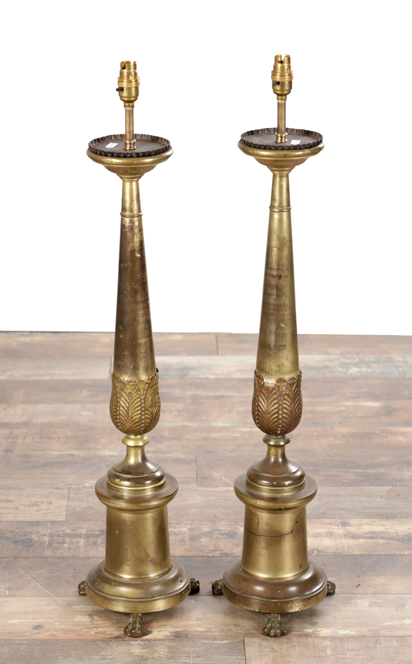 A PAIR OF LARGE BRASS CANDLESTICKS ON PAW FEET: A PAIR OF LARGE BRASS CANDLESTICKS ON PAW FEET of tapering columnar form with leaf cast lower sections and dished drip trays with pie-crust rims, on bell-turned bases with cast animal paw feet, later