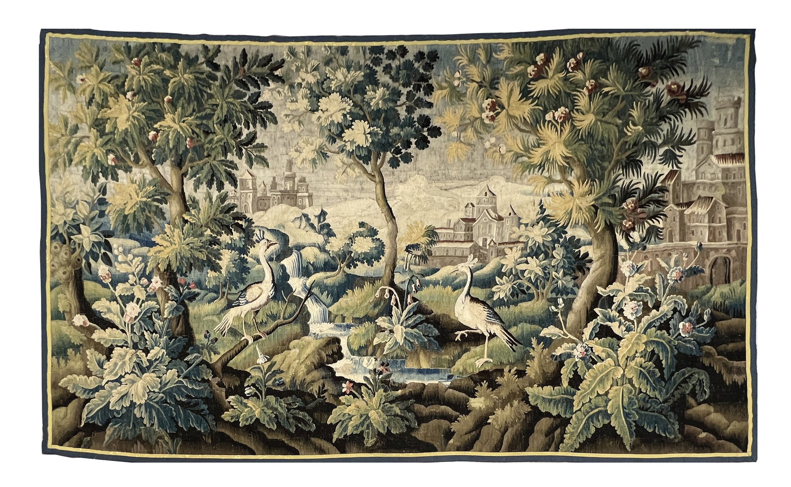 A LARGE AND IMPRESSIVE 18TH CENTURY FRENCH VERDURE TAPESTRY: A LARGE AND IMPRESSIVE 18TH CENTURY FRENCH VERDURE TAPESTRY depicting a wooded river landscape with cranes and other birds amid large-leaf foliage before a distant town and hills, within a narrow