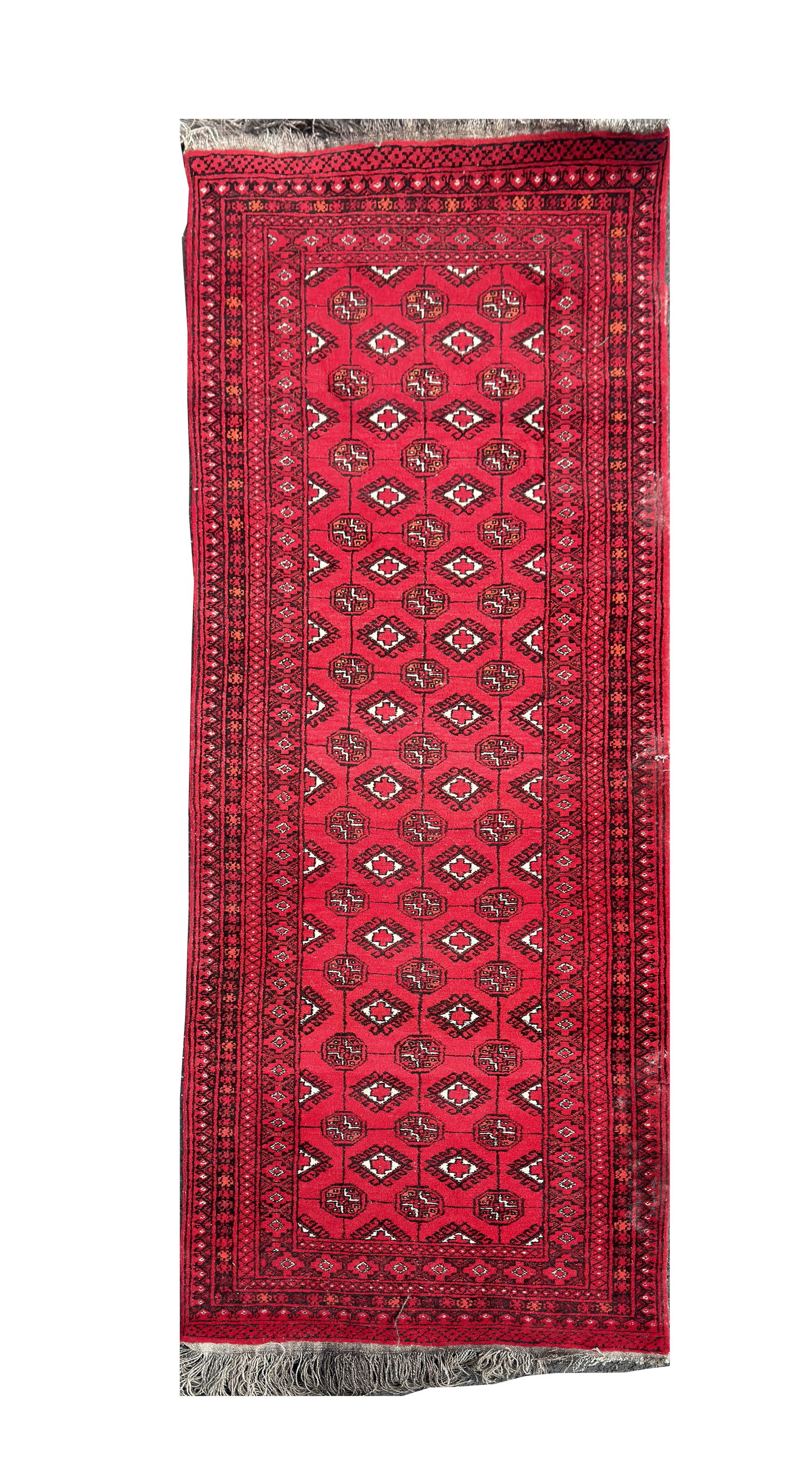 AN AFGHAN WOOL HAND KNOTTED TRIBAL CARPET: AN AFGHAN WOOL HAND KNOTTED TRIBAL CARPET with a red field patterned with repeating gul medallions and diamond motifs within multiple geometric borders, fringed ends. (275cm long, 78cm wide)