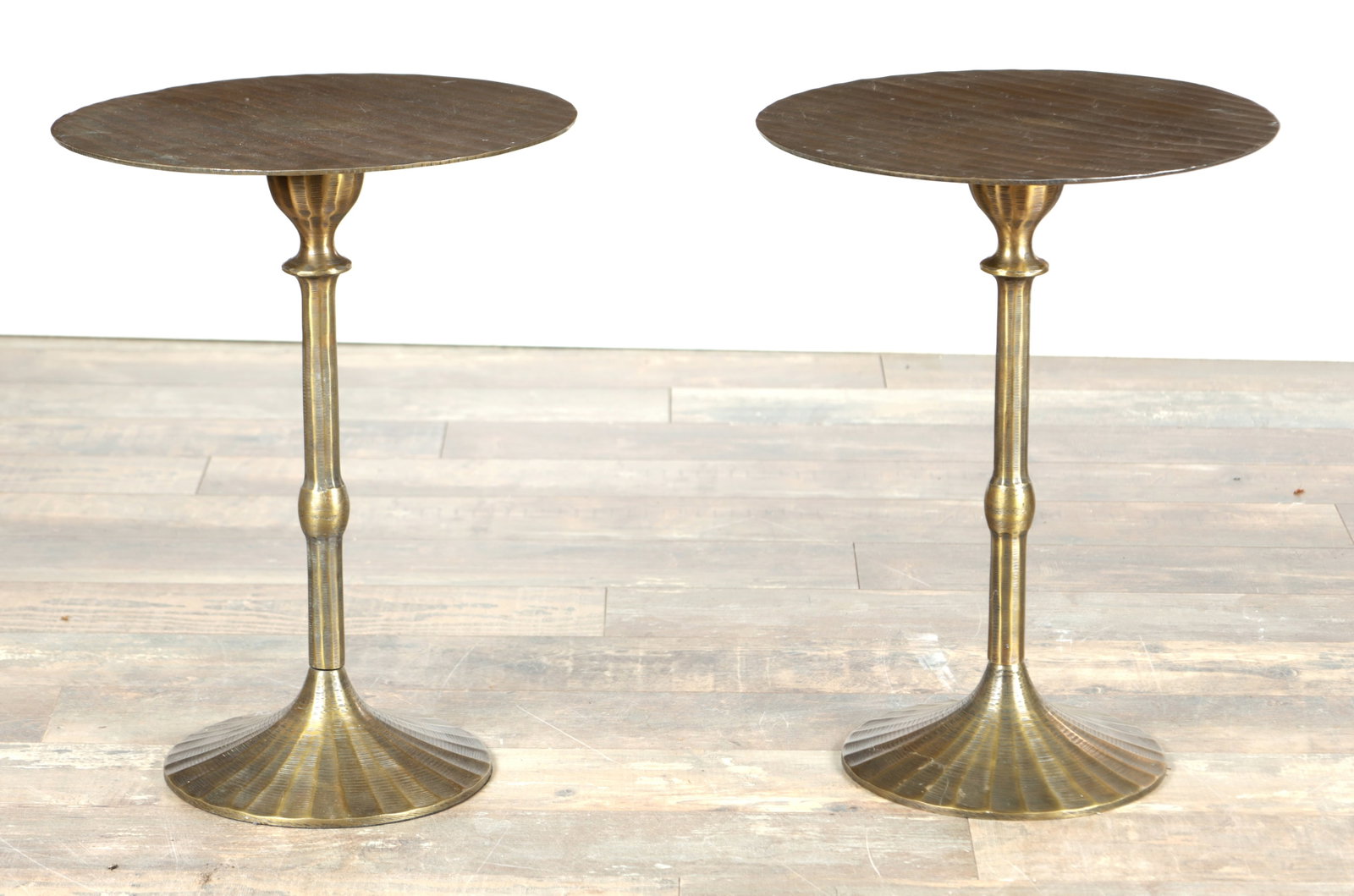 A PAIR OF BRONZED METAL SIDE TABLES WITH RITZ HOTEL PLAQUES TO THE UNDERSIDE: A PAIR OF BRONZED METAL SIDE TABLES WITH RITZ HOTEL PLAQUES TO THE UNDERSIDE each with a circular top above a slender baluster stem raised on a flared reeded circular foot. (52cm high, 39.5cm diameter