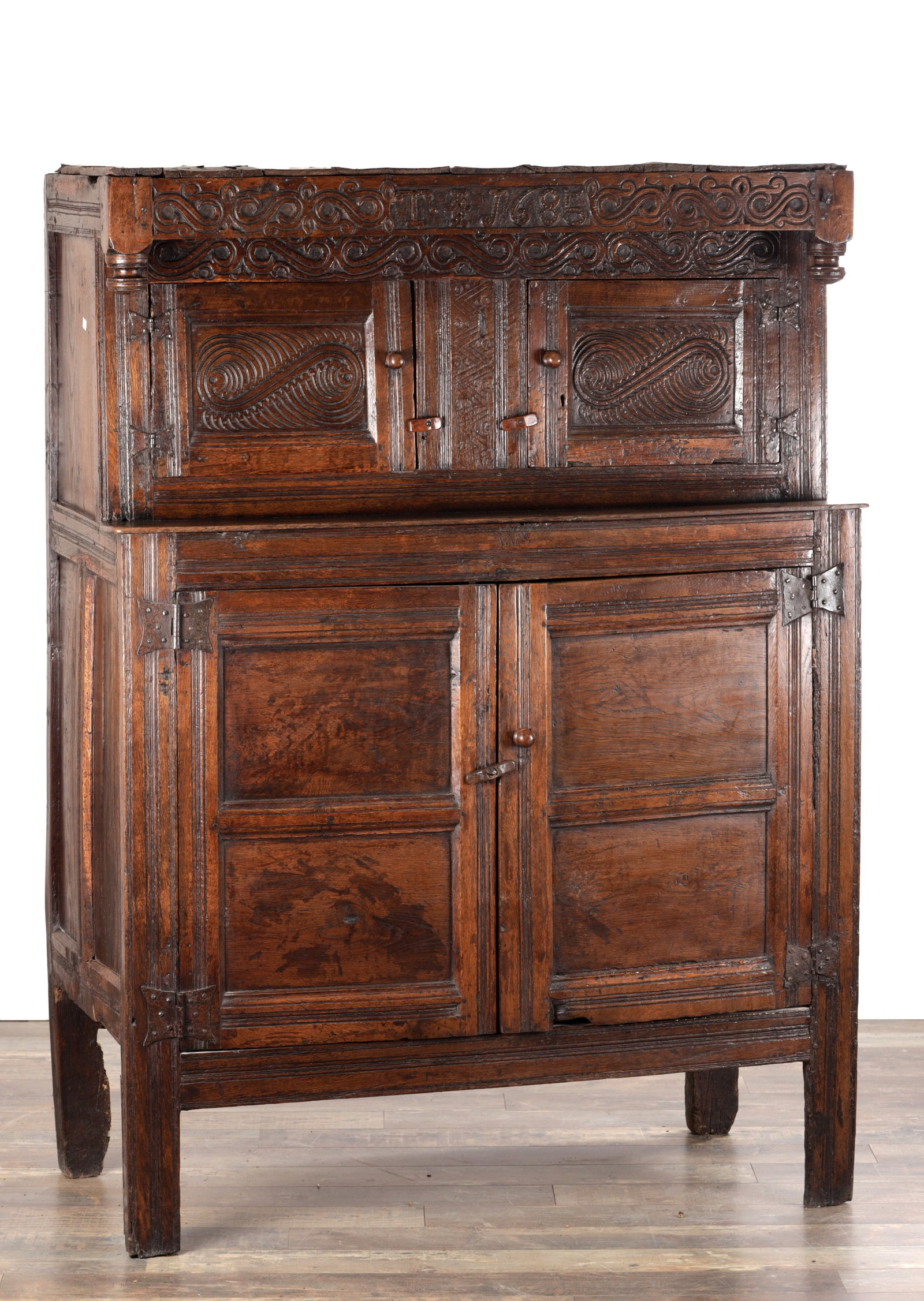 A 17TH CENTURY WESTMORLAND CARVED OAK DATED COURT CUPBOARD: A 17TH CENTURY WESTMORLAND CARVED OAK DATED COURT CUPBOARD with a scrolling carved frieze dated 1685 and initialled T I J above an enclosed upper cupboard with panelled doors, the lower section with t