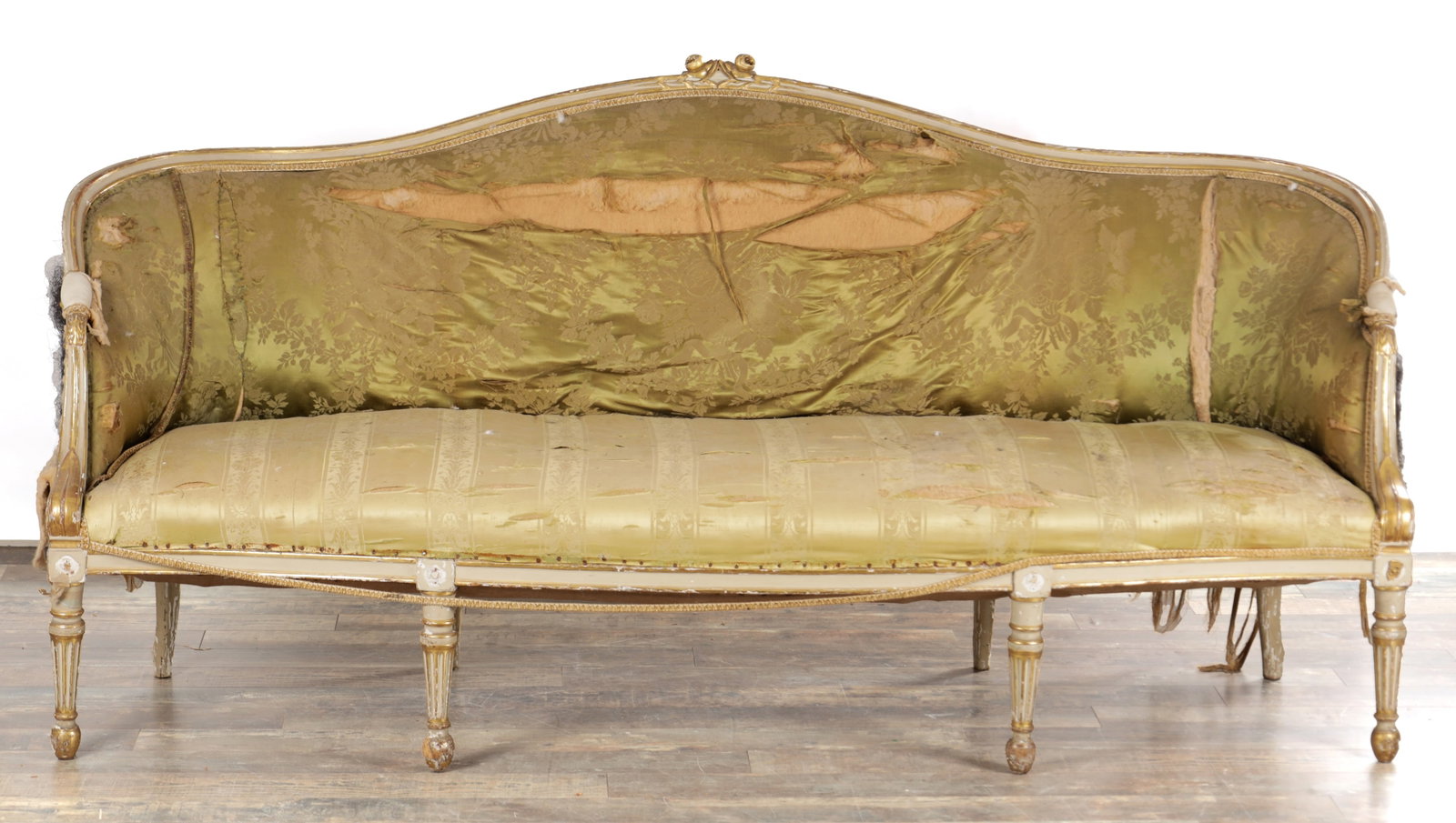 A GEORGE III PARCEL GILT AND PAINTED HEPPLEWHITE STYLE THREE SEATER SETTEE: A GEORGE III PARCEL GILT AND PAINTED HEPPLEWHITE STYLE THREE SEATER SETTEE with an arched serpentine back centred by a ribbon-tie cresting, the channelled and bead-carved frame with padded outscrolled