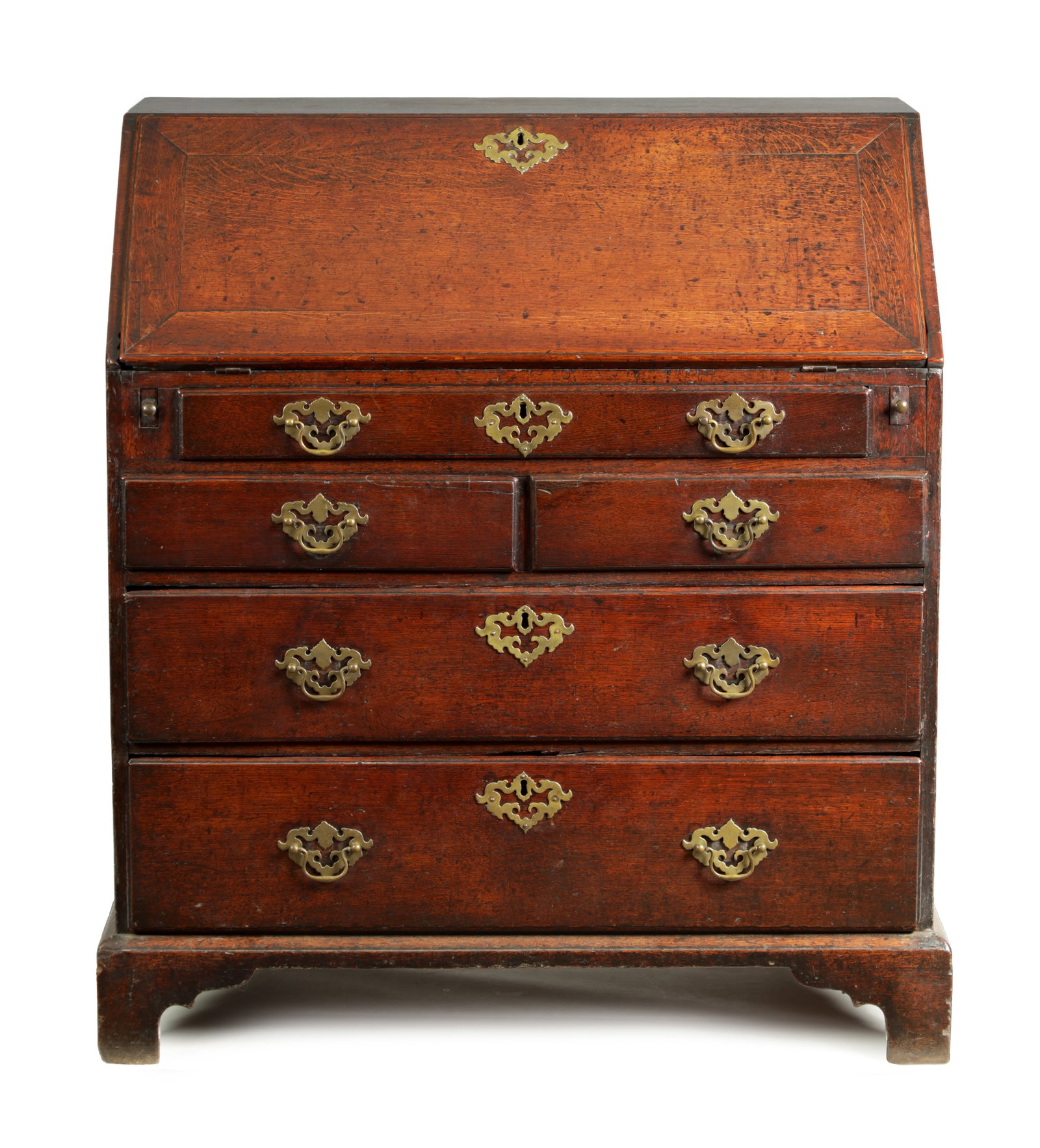 AN EARLY 18TH CENTURY OAK BUREAU WITH THREE SHORT DRAWERS: AN EARLY 18TH CENTURY OAK BUREAU WITH THREE SHORT DRAWERS the angled hinged fall front revealing a fitted interior of small drawers and pigeon holes above a shallow full-width drawer and a row of thre