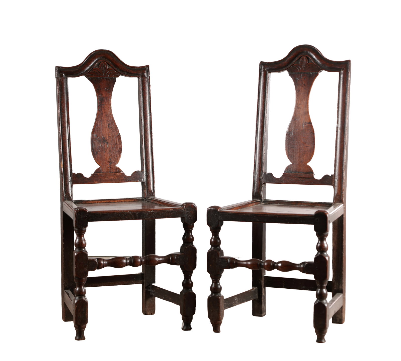 A PAIR OF WILLIAM AND MARY JOINED OAK SIDE CHAIRS: A PAIR OF WILLIAM AND MARY JOINED OAK SIDE CHAIRS with arched crestings carved with a shell above a solid vase-shaped splat, the panelled seats within moulded rails, raised on block and