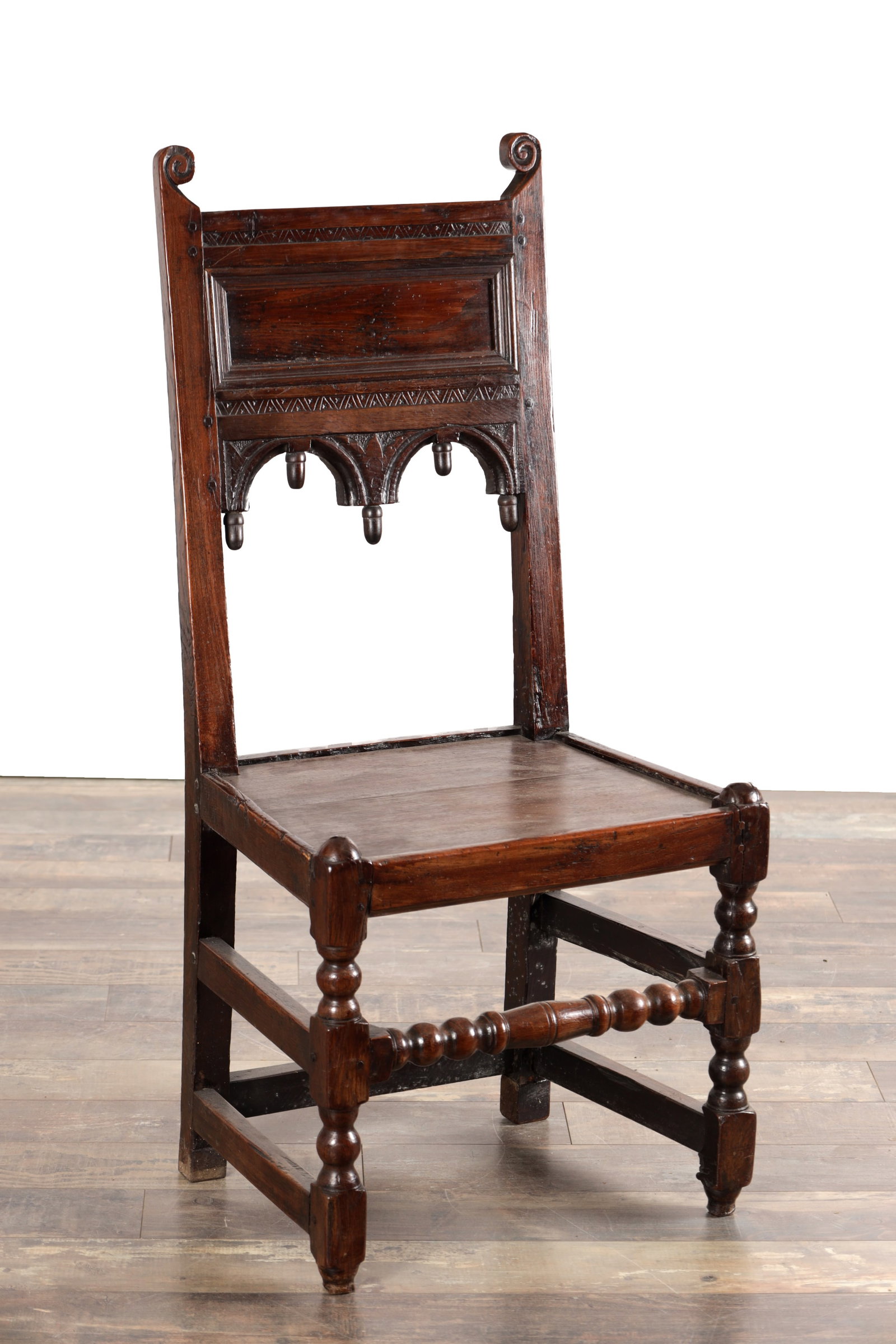 A 17TH CENTURY OAK YORKSHIRE SIDE CHAIR: A 17TH CENTURY OAK YORKSHIRE SIDE CHAIR the tall back with scrolled cresting above a moulded panel and arcaded lower rail with drop pendants, the boarded seat within a moulded frame, raised on
