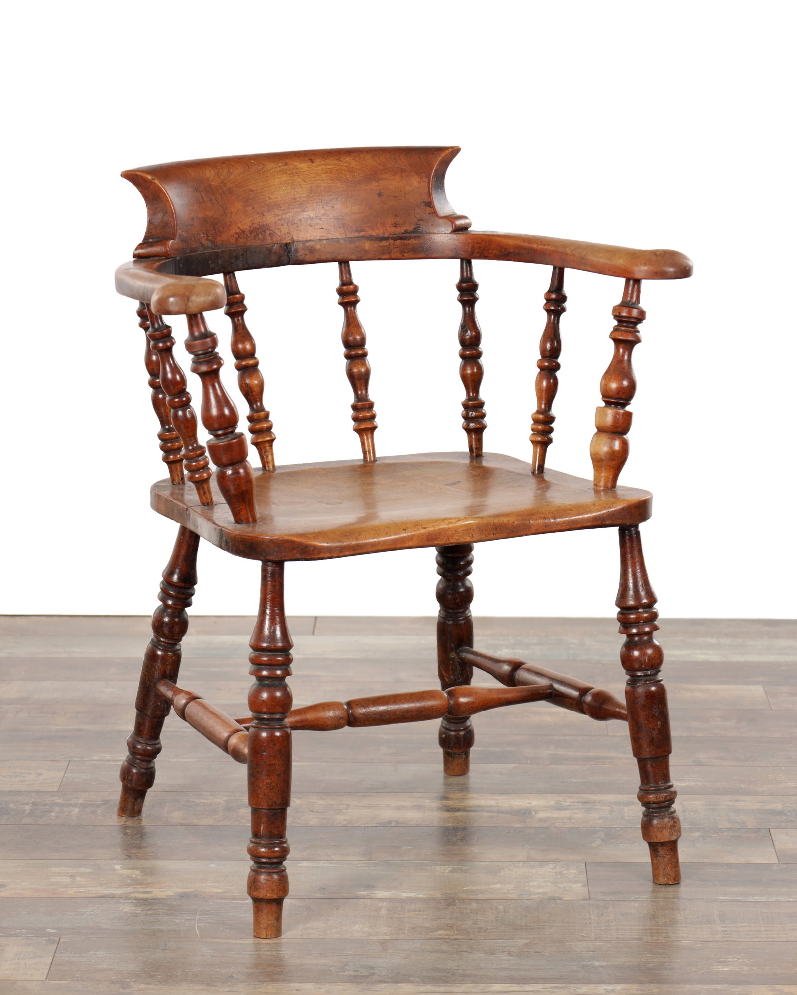 A 19TH CENTURY SOLID WALNUT SMOKERS ARMCHAIR: A 19TH CENTURY SOLID WALNUT SMOKERS ARMCHAIR with a curved back rail and wraparound arms on turned supports, a dished saddle seat, raised on ring turned legs joined by under stretchers. (65cm wide