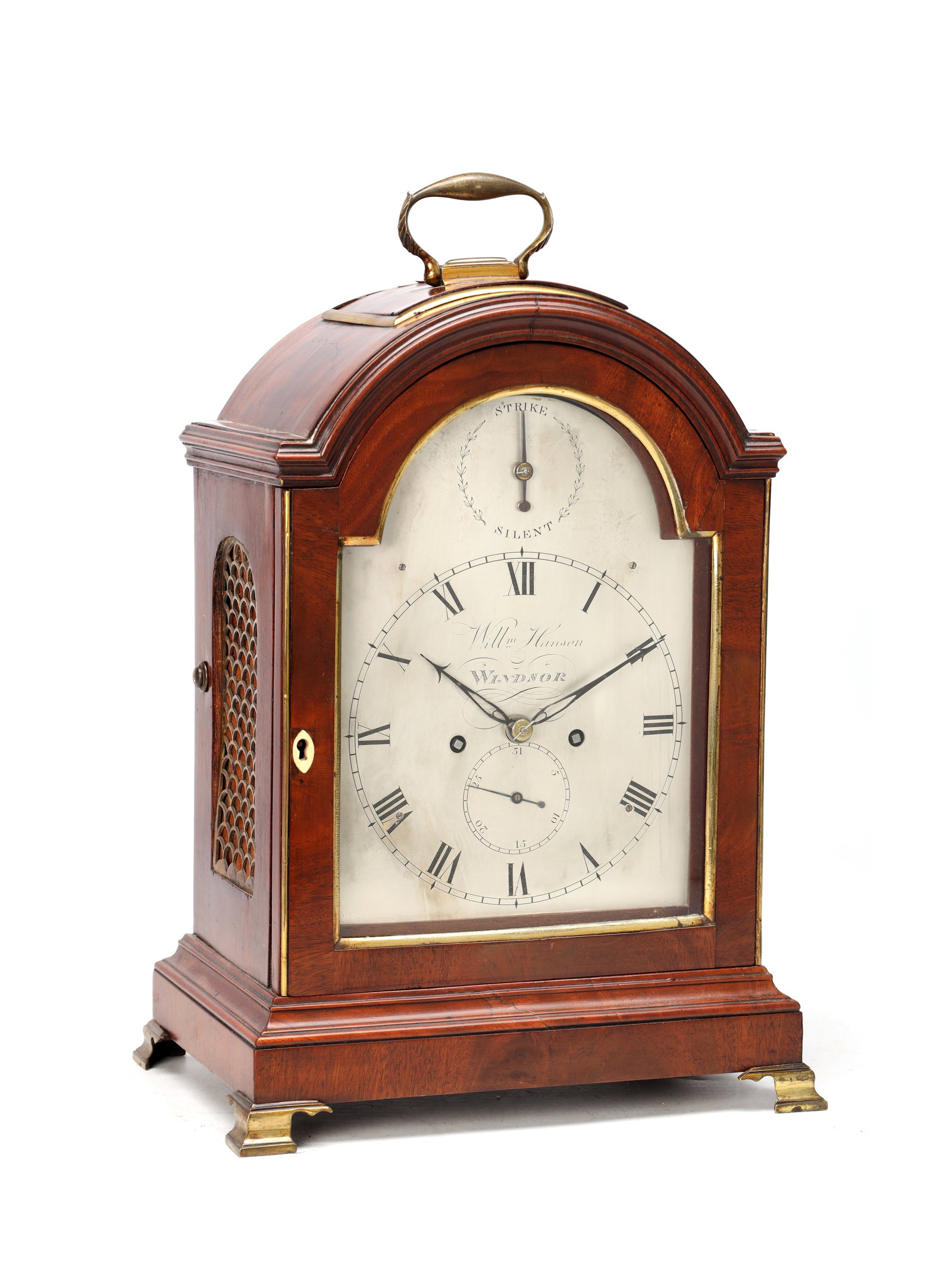 WILLIAM HANSON OF WINDSOR. A GEORGE III FIGURED MAHOGANY PAD TOP BRACKET CLOCK: WILLIAM HANSON OF WINDSOR. A GEORGE III FIGURED MAHOGANY PAD TOP BRACKET CLOCK the arched pad top case with brass carrying handle, brass moulded bezel and pierced side sound frets, raised on brass bra
