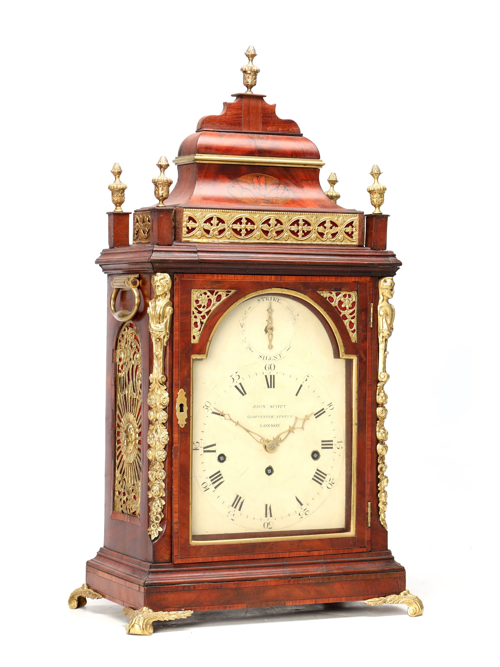 JOHN SCOTT, LONDON. A GEORGE III ORMOLU MOUNTED FIGURED MAHOGANY QUARTER CHIMING BRACKET CLOCK: JOHN SCOTT, LONDON. A GEORGE III ORMOLU MOUNTED FIGURED MAHOGANY QUARTER CHIMING BRACKET CLOCK the bell top case with stepped dome and urn finials, inlaid with Prince of Wales feathers, with pierced s