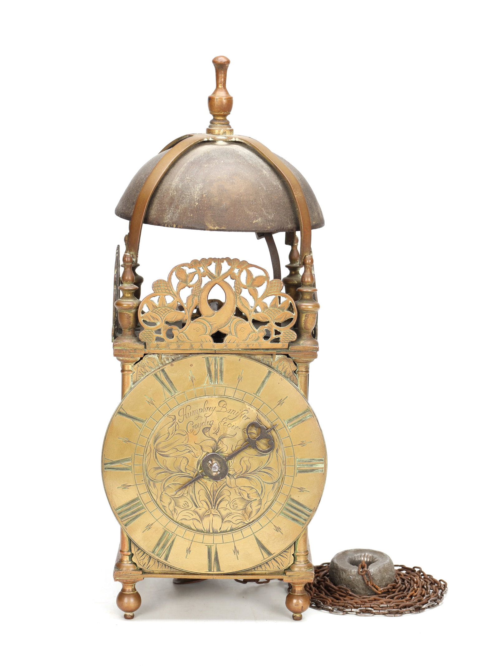HUMPHREY BANNISTER, CROYDON. A CHARLES II BRASS STRIKING LANTERN CLOCK: HUMPHREY BANNISTER, CROYDON. A CHARLES II BRASS STRIKING LANTERN CLOCK of typical strapped bell form with pierced foliate frets, turned corner columns and ball feet enclosing a 6 1/4' Roman chapter ri
