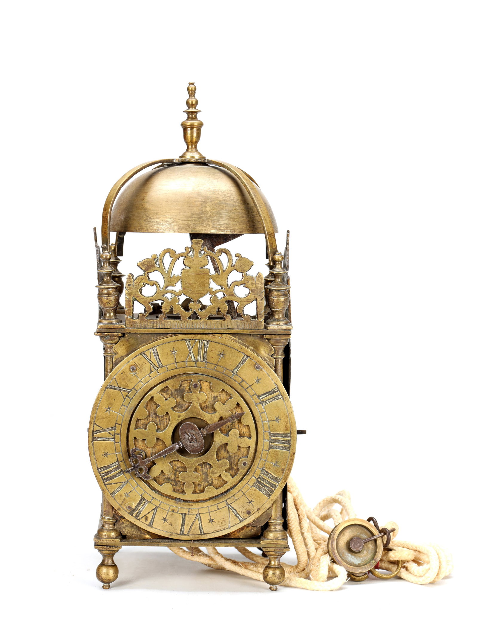A MID 17TH CENTURY BRASS STRIKING LANTERN CLOCK: A MID 17TH CENTURY BRASS STRIKING LANTERN CLOCK the posted frame with turned corner finials and ball feet, pierced foliate frets and a domed bell surmounted by a finial enclosing a 6 1/4' Roman chapte