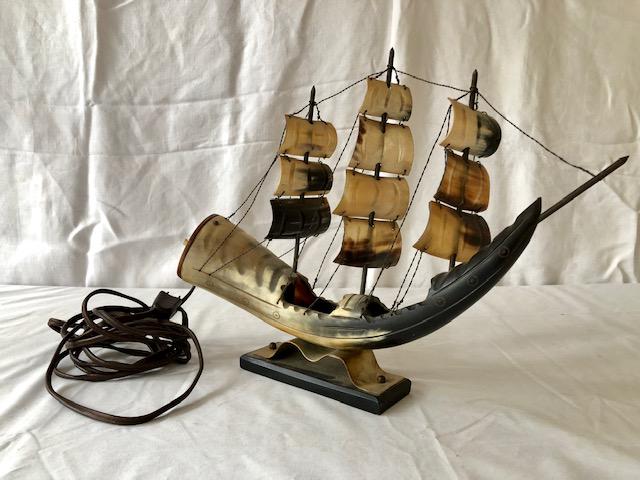 Kitsch Carved Cow Horn Sail Boat Lamp: Kitsch Carved Cow Horn Sail Boat Lamp. Works but the push-button switch sometimes sticks. With makers/origin sticker on the bottom. Figural of a sail boat. Signs of age/wear, etc. Lamp approx. 13" Lon
