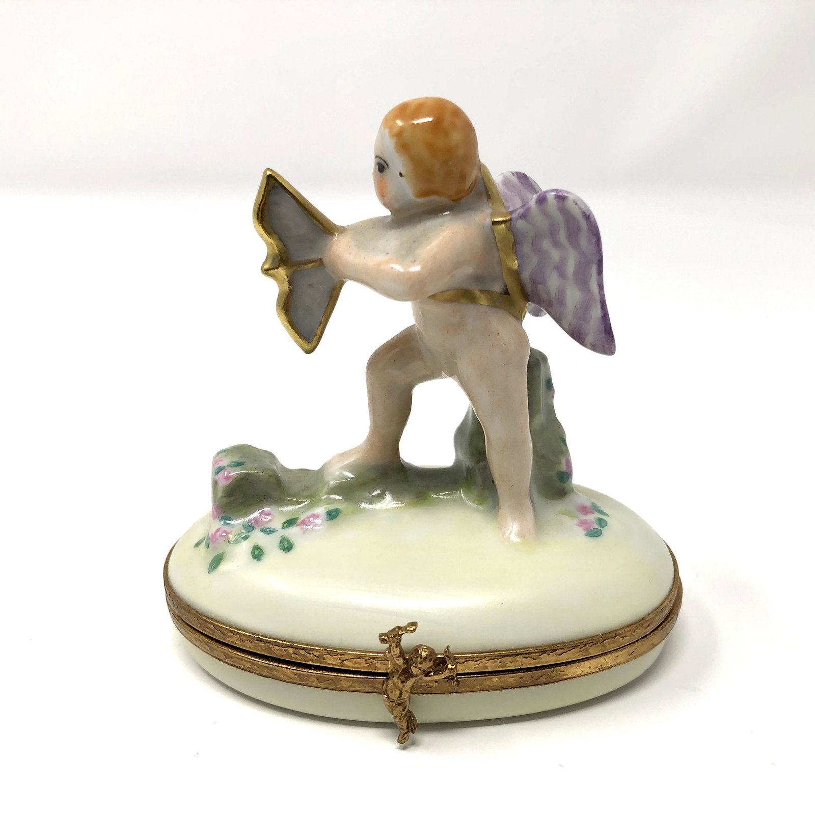 Artoria Figural Cupid and Bow Trinket Box: Artoria Figural Cupid and Bow Peint Main Limoges France Porcelain Trinket Box. Hand painted, signed and or marked. Approx. 3-inches Tall by 2 by 2 7/8 -inches In Dimension. In beautiful as-is, as-show