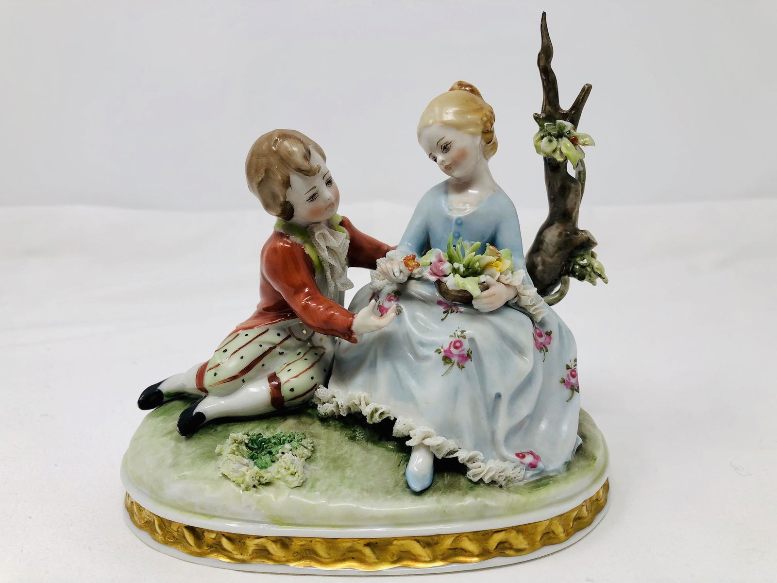 Capodimonte Porcelain Figurine Group Courting Secene: Capodimonte Style Porcelain Figurine Group of a Courting Scene, boy and girl near a tree. Approx. 5 1/2-inches Tall by 5 1/2-inches Long by 4-inches Deep. In beautiful condition as-Is, as-shown.