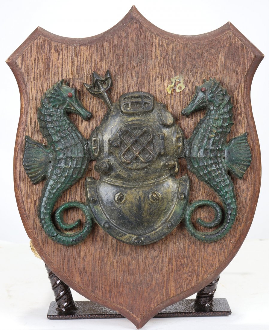 US Navy Mark V Diving Helmet Plaque w/ Seahorses: This is a good looking brass and wood plaque featuring a Mark V helmet. Classic seahorses on each side of the helmet and a trident (one broken off). Wood base measures 13 inches tall and 10.5 inches w