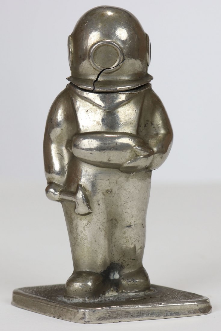 Vintage Made In Japan Diver Figure Cigarette Lighter: Charming diver figure measuring 3.5 inches tall, made of metal and platted. Bottom marked Made In Japan. The divers helmet hinges back to expose the lighter. Front of helmet is cracked. Wonderful rare