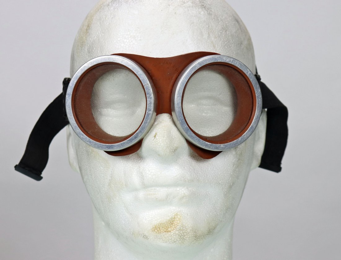 British Navy WW2 Goggles: Rubber surrounding the windows, might be aluminum around the lense, elastic black band on the back, lenses seem to be glass, good condition, unshatterabler is on the left side printed on the rubber an