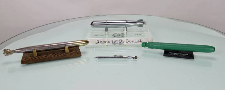 Four Vintage Submarine Torpedo Models: This is a grouping of four vintage submarine torpedo models. The first piece is a chrome torpedo displayed on a wood base. It weighs 1 pound and the torpedo comes off the stand and it is 9.75 inches