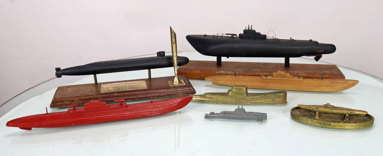 Seven Vintage Submarine Models: This grouping consists of 7 different vintage submarine models. The first piece is a large black submarine on wood base. The submarine model is wood as well. The base measures 13.25 inches long. The