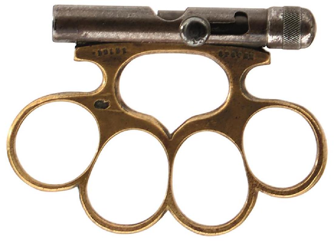 A RARE EARLY 20TH CENTURY APACHE COMBINATION KNUCKLE: A RARE EARLY 20TH CENTURY APACHE COMBINATION KNUCKLE GUN, the brass knuckle body of characteristic form stamped with the manufacturer's details and the date stamp for 1913, the palm end with brazed 7.