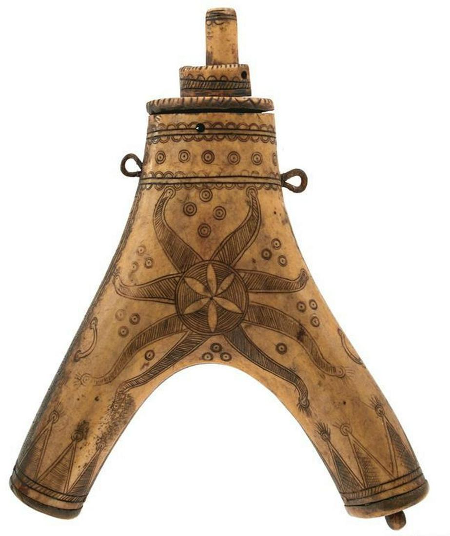 A LATE 17TH CENTURY OR 18TH CENTURY GERMAN OR POSSIBLY: A LATE 17TH CENTURY OR 18TH CENTURY GERMAN OR POSSIBLY HUNGARIAN HORN POWDER FLASK, of characteristic Y form, profusely decorated with concentric circles and a star form, natural horn reverse, two iro