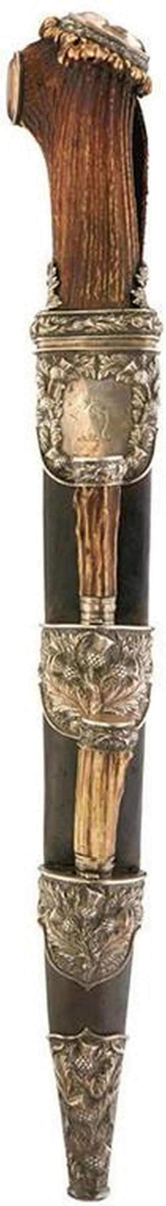 A SCOTTISH SILVER MOUNTED DRESS DIRK, 29cm blade with: A SCOTTISH SILVER MOUNTED DRESS DIRK, 29cm blade with faceted back edge, natural stag horn hilt set with two faceted stones, silver mounts embossed with thistles, contained in its leather scabbard wit