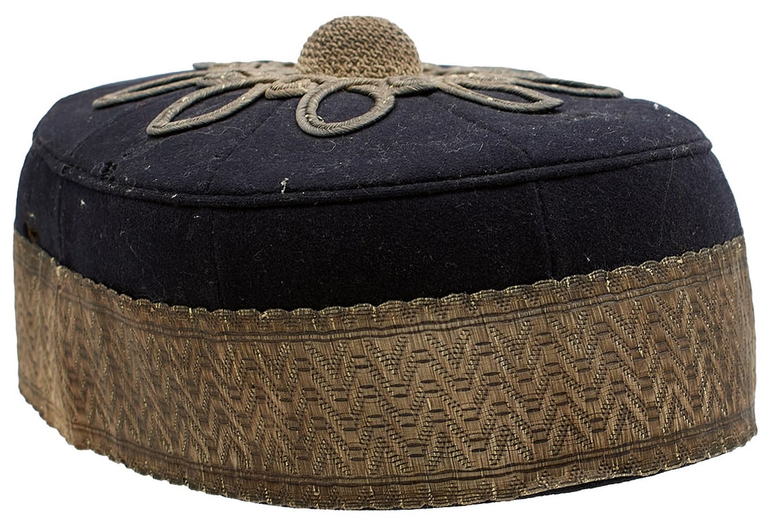 TWO VICTORIAN OFFICER'S PILL BOX HATS,: TWO VICTORIAN OFFICER'S PILL BOX HATS, the first of black cloth segments, silver bullion ribbon trim, the top with foliate bullion adornment with matching central boss, leather and red silk liner with