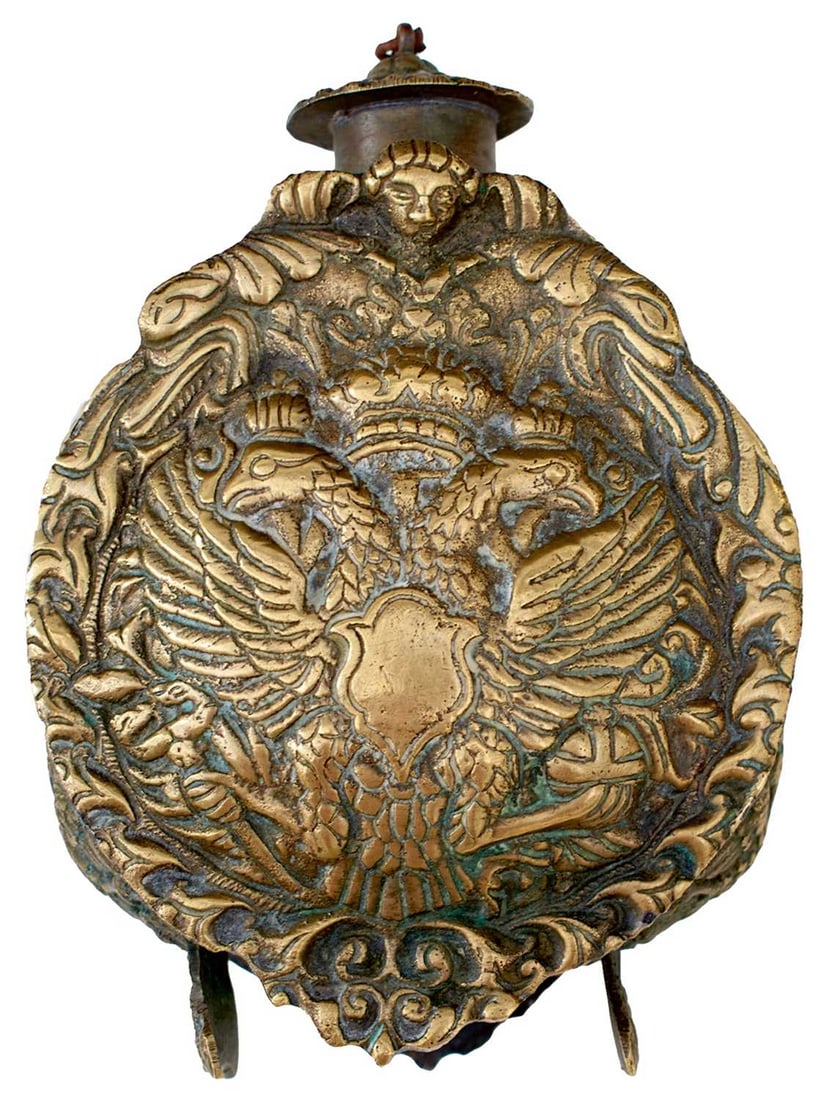 AN 18TH CENTURY RUSSIAN BRASS POWDER FLASK: AN 18TH CENTURY RUSSIAN BRASS POWDER FLASK decorated in high relief with a coat of arms with the Russian royal double headed eagle below winged cherub's head to both sides, small crest to both ends, 1