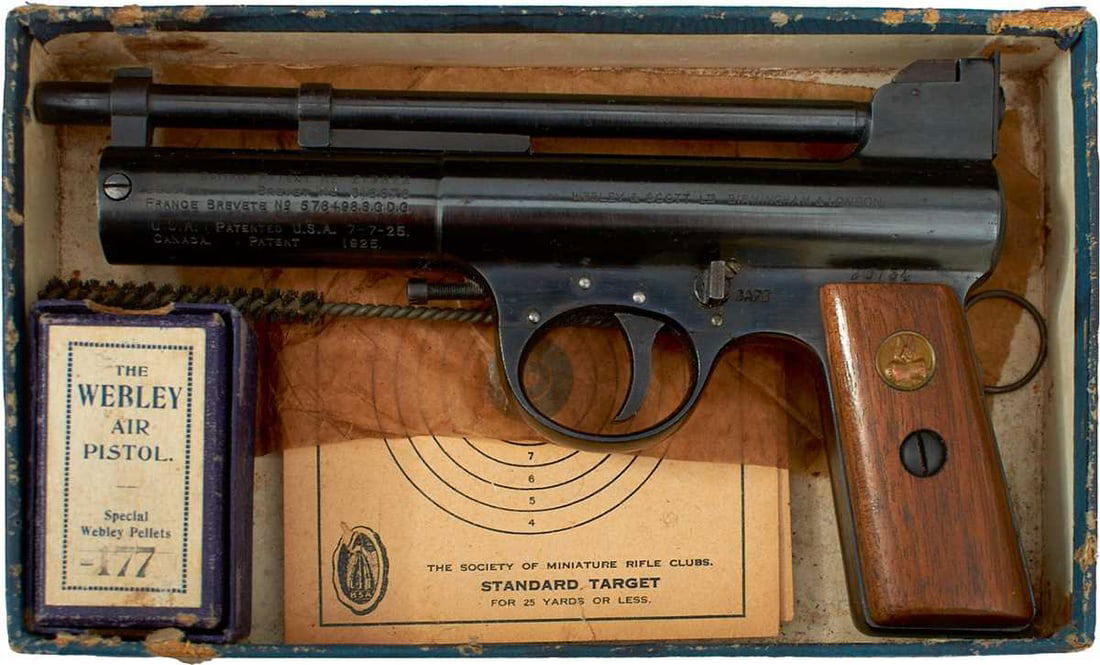 AN ANTIQUE BOXED .177 CALIBRE WEBLEY AIR PISTOL MARK I,: 7inch sighted blued barrel, the blued cylinder stamped with Model and manufacturer's details, serial no. 20734, two-piece wooden grips, the left inset with the brass winged pellet emblem, in its card