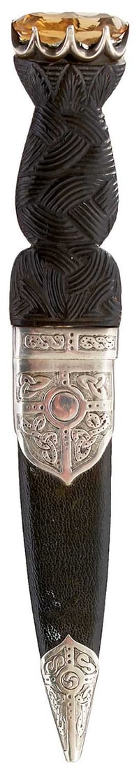 A SCOTTISH SILVER MOUNTED SGIAN DUBH,: 8.5cm fullered blade (tip chipped) with partially faceted back edge, wooden grip (some splits) carved with Celtic knotwork to the front and with entwined knotwork collar, amber coloured stone pommel,