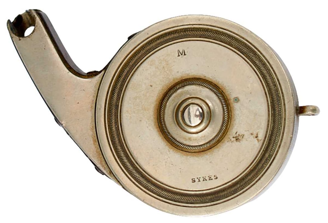 A SYKES LONG-NOSED PERCUSSION CAP DISPENSER,: the ringturned white metal body stamped SYKES to the front, blued spring, suspension loop.