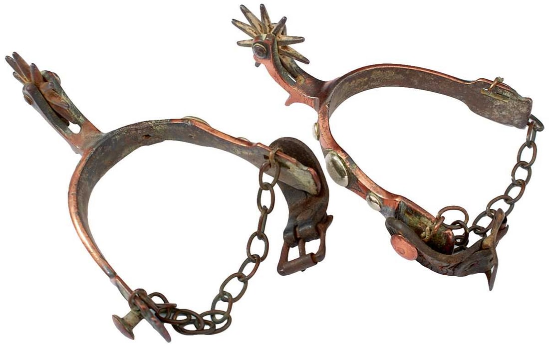A PAIR OF LATE 19TH CENTURY AMERICAN SPURS BY NORTH & JUDD OF CONNECTICUT,: the maker marked (anchor) copper plated arms with domed white metal decoration, (one stud lacking), spiked rowels, leather buckles, later chains, together with an Indian polished bone and glass bead