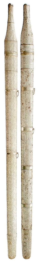 A CASED PAIR OF WHITE METAL MOUNTED OMANI KATTARA,: each with 80cm triple fullered blade, characteristic white metal hilts embossed with panels of scrolling foliage and geometric designs, in their white metal wrapped wooden scabbards, decorated to