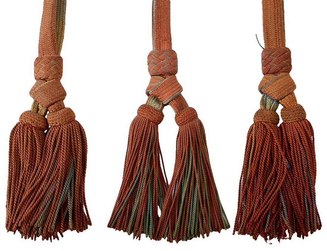 THREE SECOND WAR PERIOD IMPERIAL JAPANESE SWORD KNOTS,: two of brown and blue cloth and the last of gold and brown, all with their double tassels.