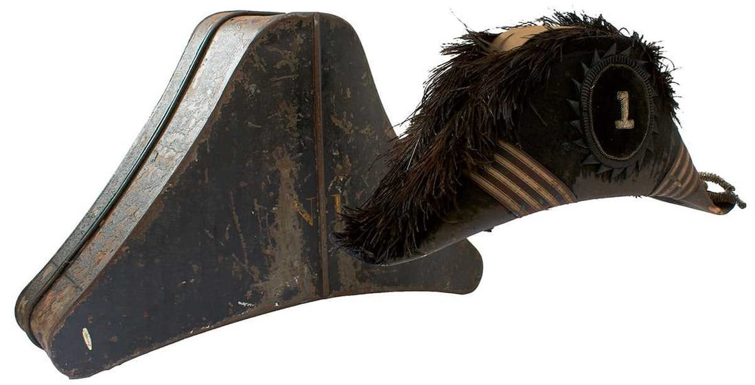 A CONFEDERATE MARINE OFFICER'S BICORN HAT AND TIN.: the black fur covered body with feather top, black and silver bullion striped trim with bullion tassel to one peak, the front with cloth and velvet trimmed insignia with central numeral 1, leather
