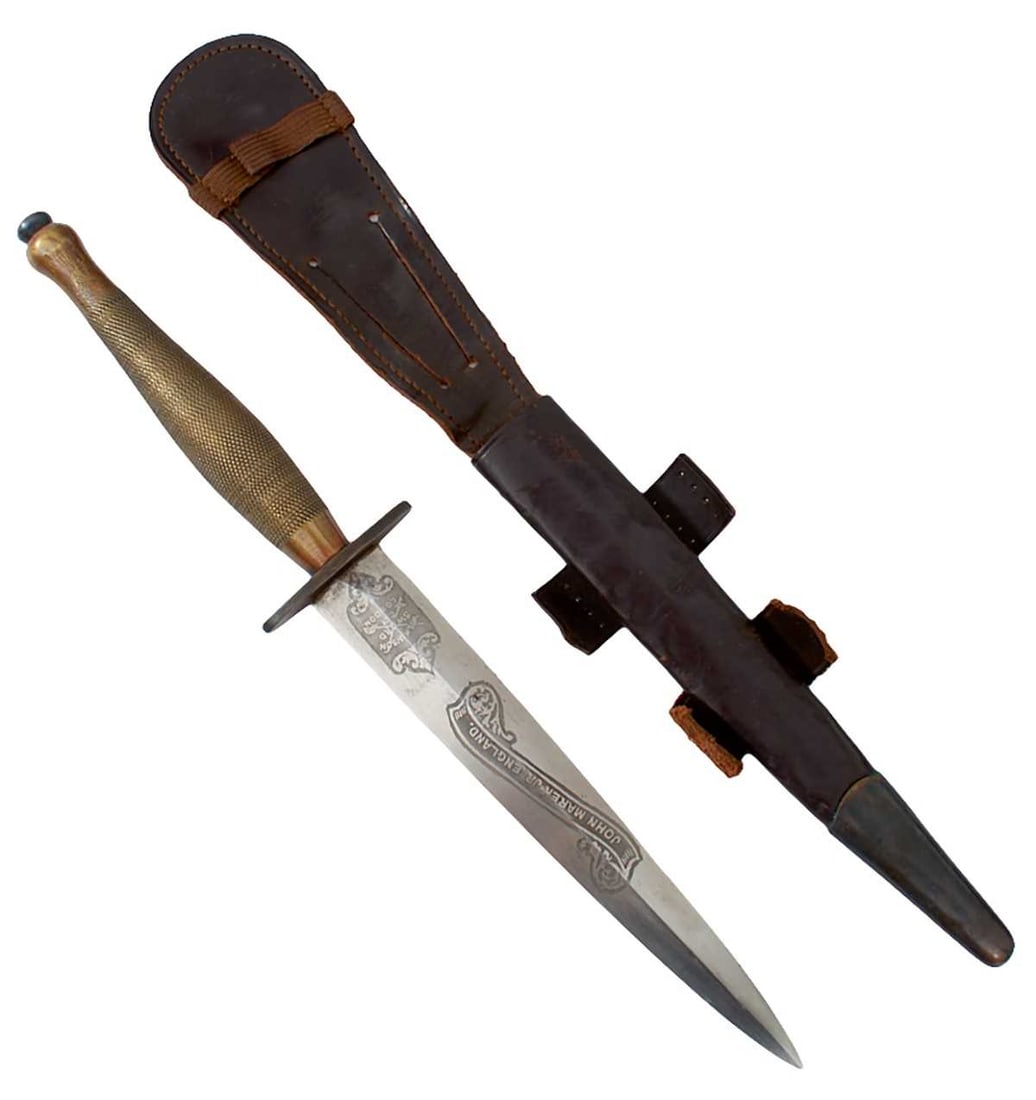 A SECOND PATTERN FAIRBAIRN SYKES COMMANDO KNIFE OR DAGGER,: 17cm flattened diamond section blade etched with a maker's panel for Wilkinson and the owner's name John Marek Junior, regulation steel and brass hilt with chequered grip, in its leather sheath. A