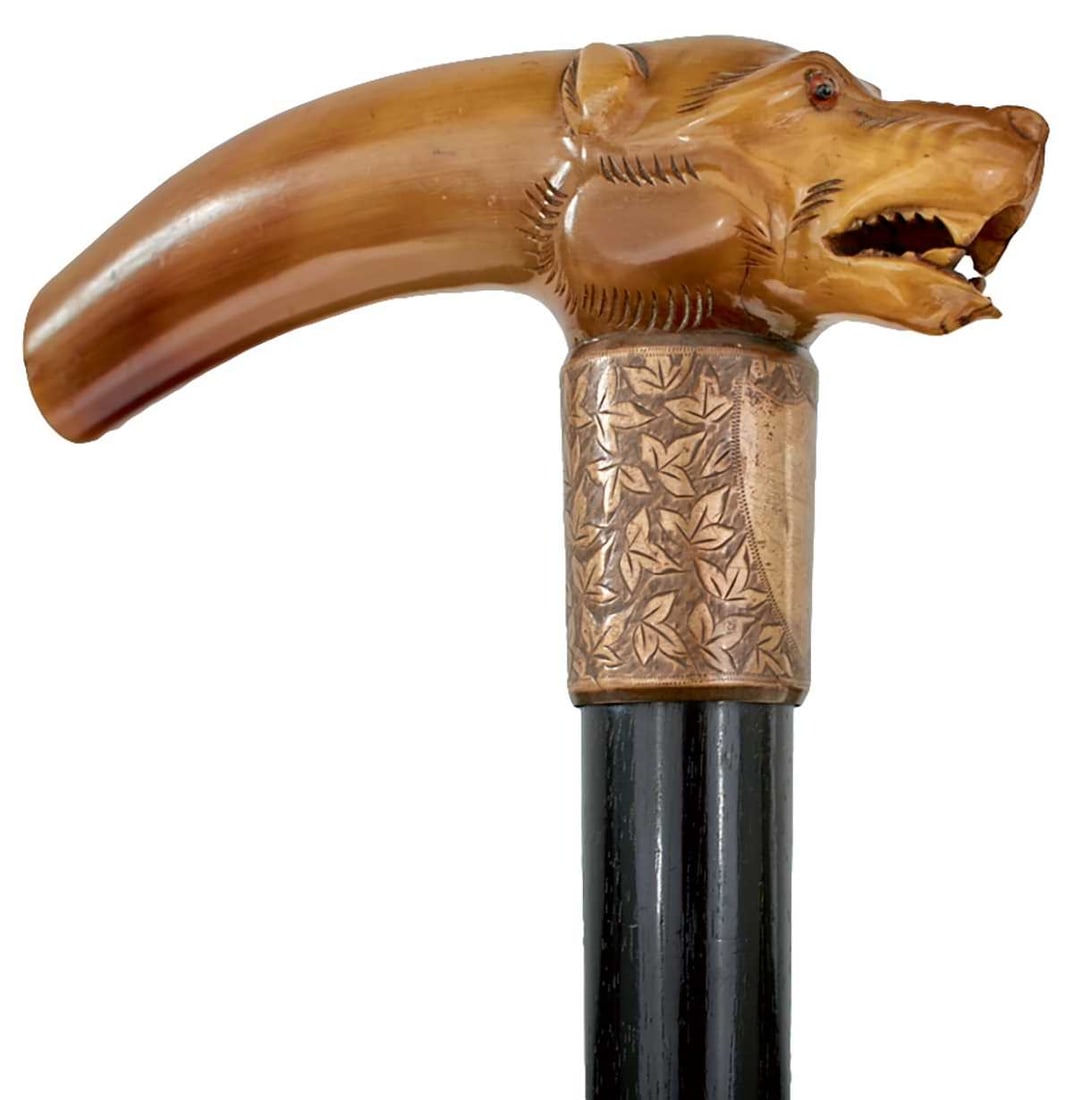 A LATE 19TH CENTURY DOG'S HEAD WALKING STICK,: the horn L-shaped handle carved in the form of a dog's head (one glass eye missing), foliate engraved silver collar with vacant shield with Birmingham hallmarks and maker's mark for George Loveridge