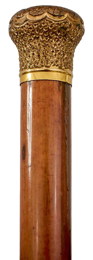 A 19TH CENTURY WALKING STICK,: gilt metal pommel, tapering malacca haft, metal ferrule, 90cm long over all.