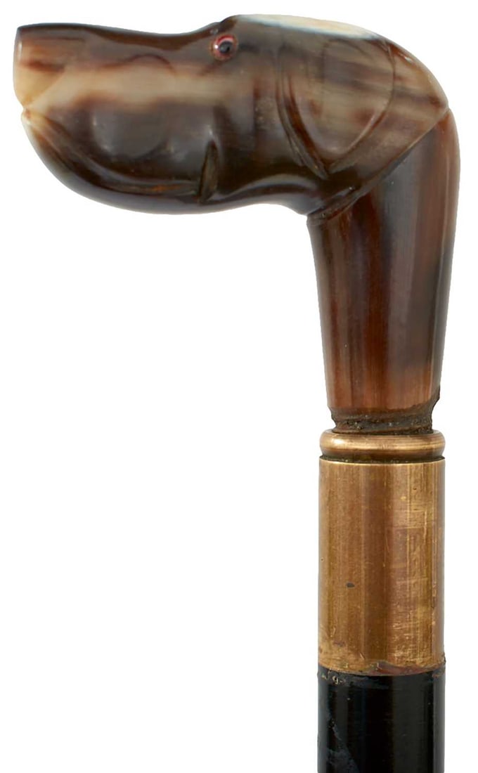 AN ART DECO HUNTING BOOT HORN,: 31.25cm over all length, horn pommel carved with a hound's head, unscrewing to reveal a 10.5cm triangular section blued blade, ebonised haft, horn slide. Circa 1910.