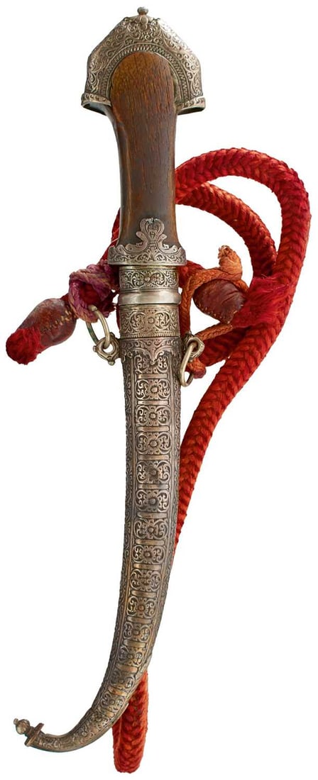 A 19TH CENTURY MOROCCAN KOUMMYA OR JAMBIYA,: A 19TH CENTURY MOROCCAN KOUMMYA OR JAMBIYA, 23cm curving double edged blade, characteristic white metal mounted hilt decorated with panels of foliage, possibly rhinoceros horn grip, contained in its