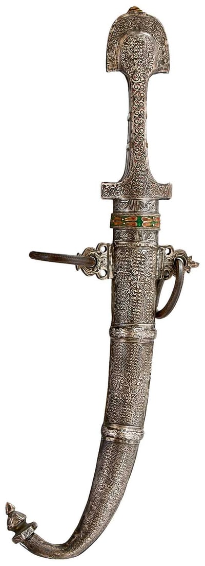 A LATE 19TH CENTURY MOROCCAN KOUMMYA OR JAMBIYA,: A LATE 19TH CENTURY MOROCCAN KOUMMYA OR JAMBIYA, 23.5cm curved blade, double edged towards the tip, characteristic hilt pf brass with white metal face chiselled with fine scrolls and with enamelled