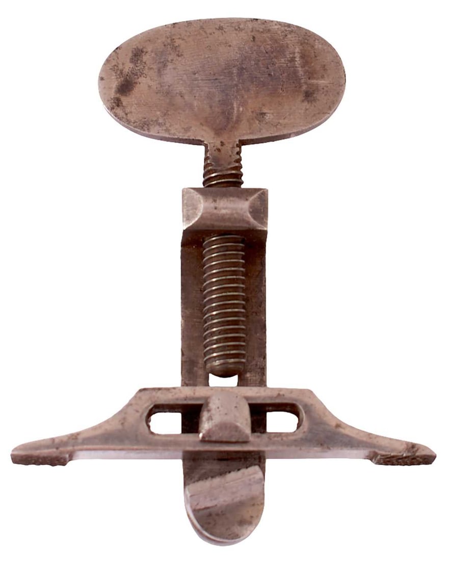 A MAIN SPRING CLAMP,: A MAIN SPRING CLAMP, the case colour hardened body with oval top, stamped B, burnished steel jaws.