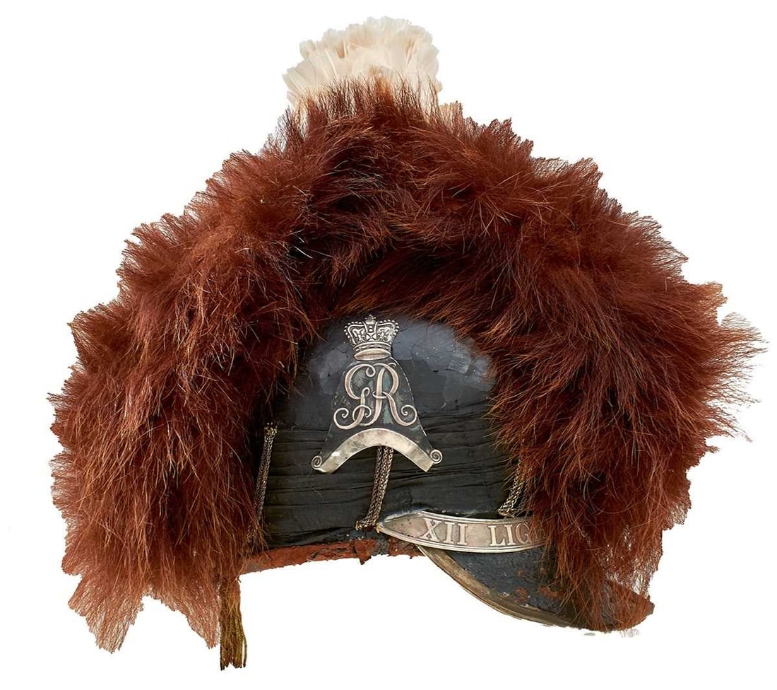 A VERY RARE OFFICER'S TARLETON OF THE 12TH LIGHT DRAGOONS,: A VERY RARE OFFICER'S TARLETON OF THE 12TH LIGHT DRAGOONS, the black leather skull with white metal mounts, the right side mounted with a crowned GR surmounting a scroll form, the head band embossed X