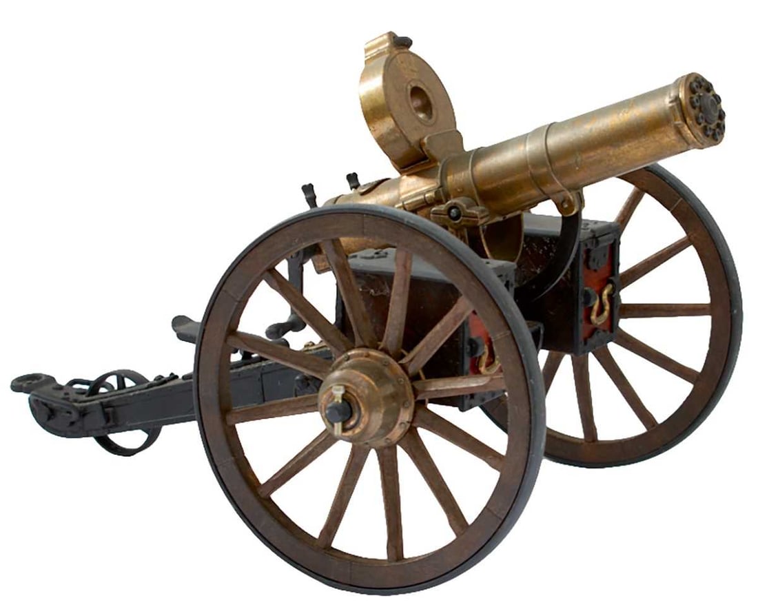A DESK SIZED MODEL 1883 GATLING GUN,: A DESK SIZED MODEL 1883 GATLING GUN, 8.25inch multi-stage brassed barrel with magazine, black painted cast metal carriage with metal trimmed wood effect wheels, complete with its original box. 38cms o