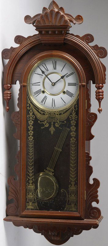 Large Victorian Style Wall Regulator Clock: With a carved crest over a large arched molded top, the clock dial has an enameled finish with gilt reverse painted tablet, clock measures 36" H x 16" W x 6" D.
