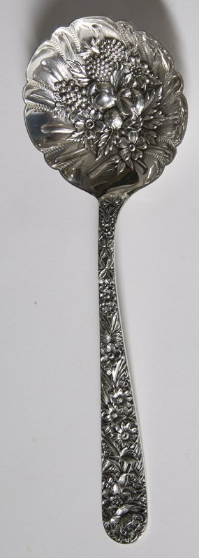 S. Kirk & Son Repousse Sterling Berry Spoon: Large berry spoon with no monogramme. Floral decorations adorn handle and the spoon is of various fruit and flowers. Marked S. Kirk & Sons, Sterling. 120 grams total weight. Minor surface scratches.