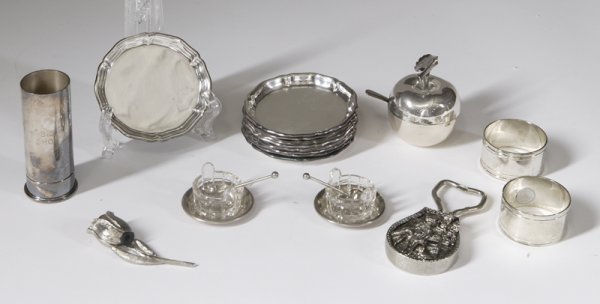 18 Pieces of Silver Plated Articles: To include a pair of napkin holders, a 2-ounce shot glass jigger, a covered apple mustard jar, a lying rose slat shaker, 9 small plates, a heavy weighted bottle opener and a pair of salt dips with spo